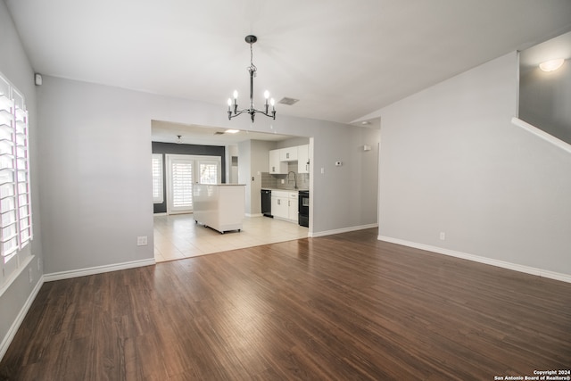 unfurnished living room featuring sink, light hardwood / wood-style floors, and a notable chandelier