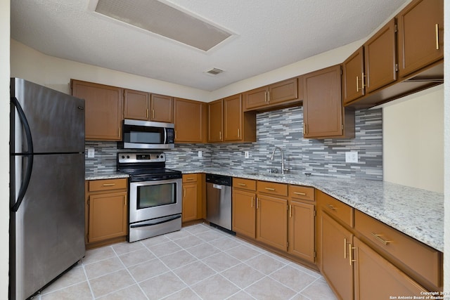 kitchen featuring decorative backsplash, light tile patterned floors, sink, and appliances with stainless steel finishes