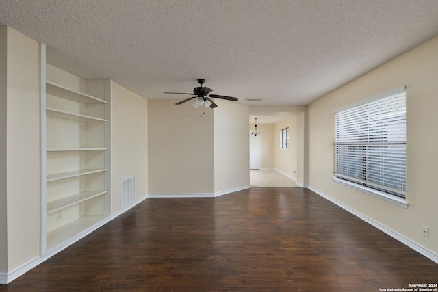 spare room with dark hardwood / wood-style floors, built in features, a textured ceiling, and ceiling fan with notable chandelier