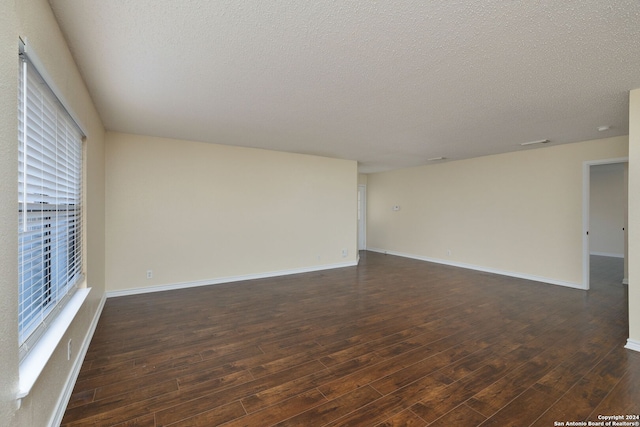 unfurnished room with a textured ceiling and dark wood-type flooring