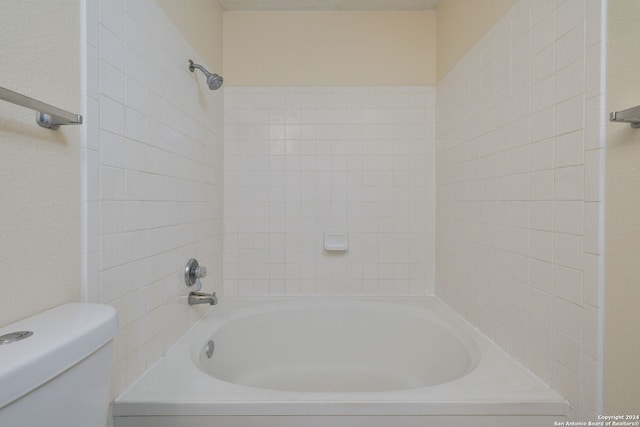 bathroom with toilet and tiled shower / bath