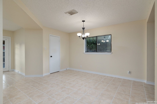 tiled empty room featuring a chandelier and a textured ceiling