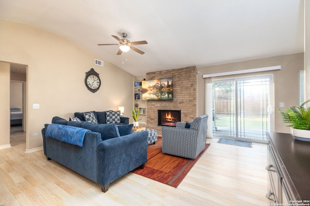 living room with ceiling fan, a fireplace, vaulted ceiling, and light wood-type flooring