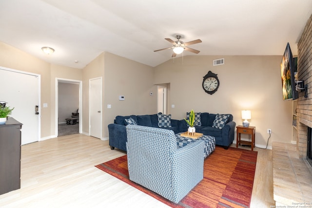 living room featuring light wood-type flooring, a brick fireplace, ceiling fan, and lofted ceiling