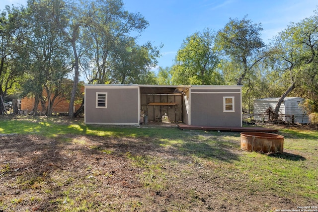 back of house with a storage unit and a lawn