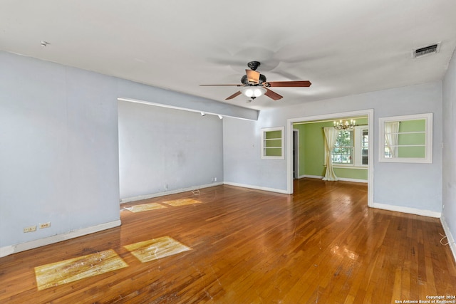 spare room with hardwood / wood-style floors and ceiling fan with notable chandelier