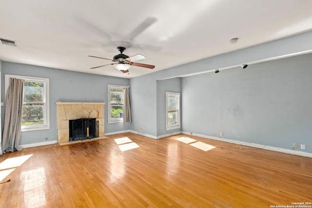 unfurnished living room with ceiling fan, a fireplace, and light hardwood / wood-style flooring