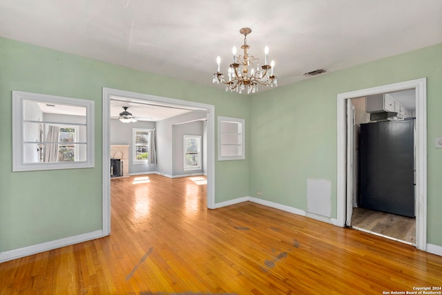 empty room featuring hardwood / wood-style floors and ceiling fan with notable chandelier