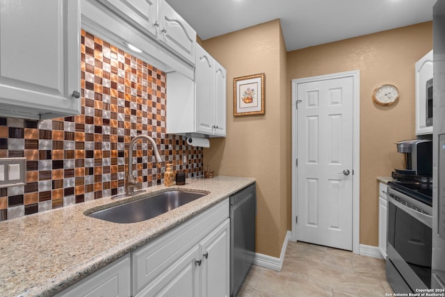 kitchen featuring appliances with stainless steel finishes, tasteful backsplash, light stone counters, sink, and white cabinets