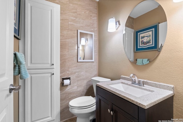 bathroom with vanity, toilet, and tile walls