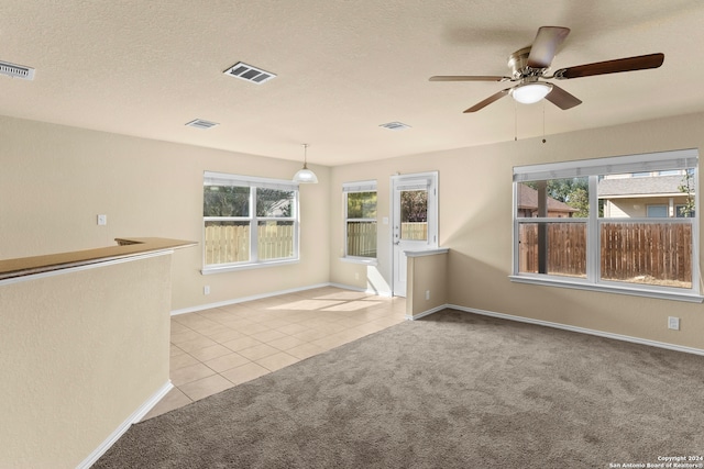 carpeted spare room featuring ceiling fan, plenty of natural light, and a textured ceiling