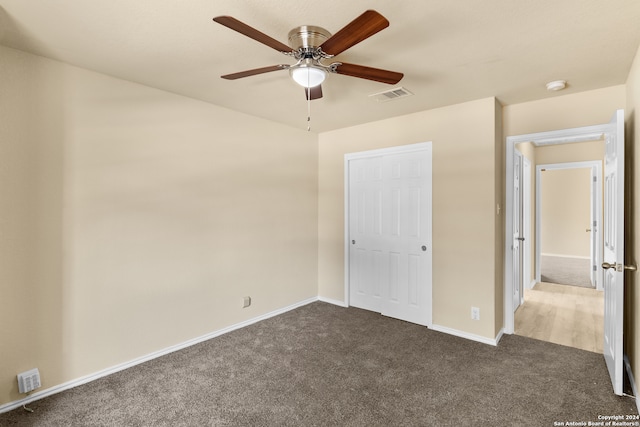 unfurnished bedroom with a closet, dark carpet, and ceiling fan