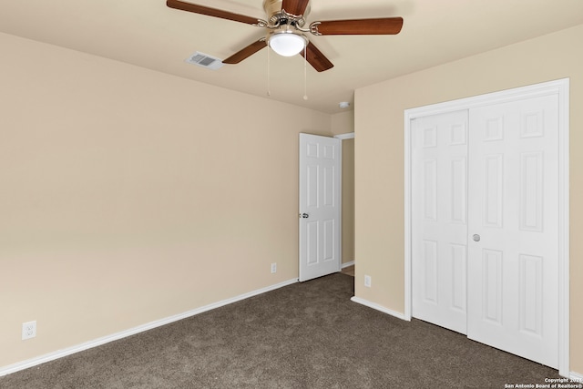 unfurnished bedroom with dark colored carpet, ceiling fan, and a closet