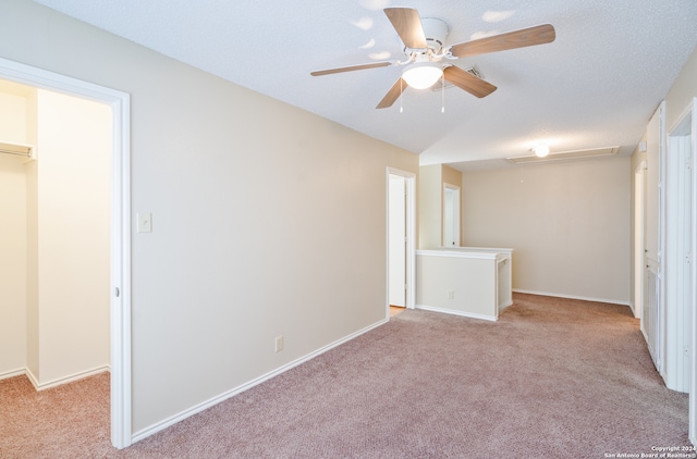 unfurnished bedroom featuring light carpet, a textured ceiling, a closet, and ceiling fan