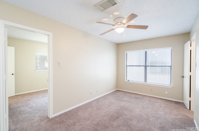 unfurnished room featuring ceiling fan, light colored carpet, and a textured ceiling