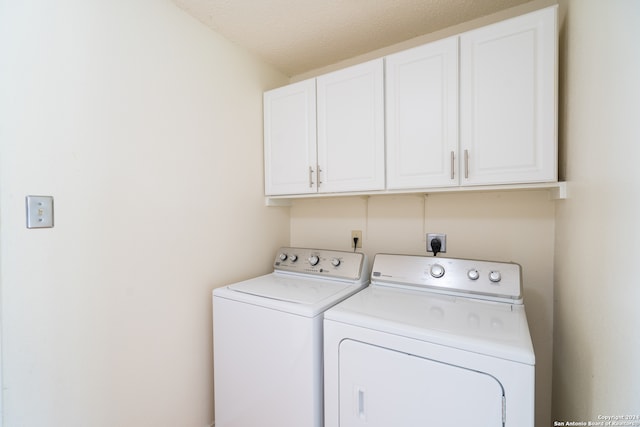 clothes washing area with cabinets, a textured ceiling, and washer and clothes dryer