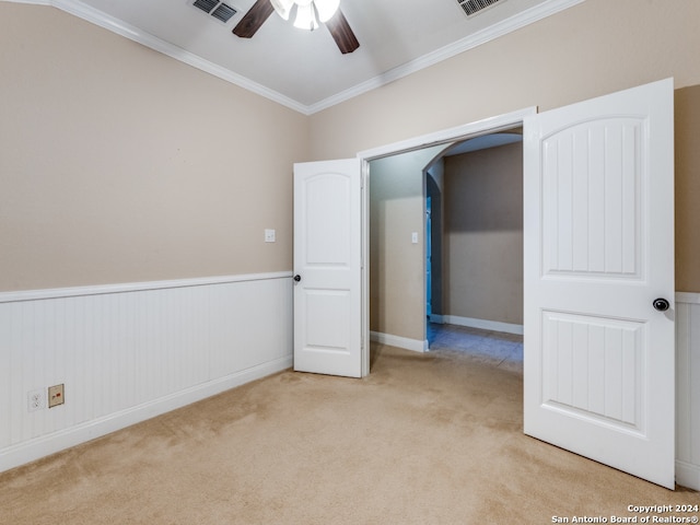 carpeted empty room featuring ceiling fan and crown molding