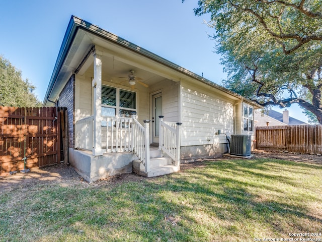 rear view of property featuring ceiling fan, a yard, and central AC