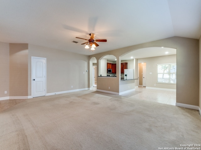 unfurnished living room featuring ceiling fan, lofted ceiling, and light carpet