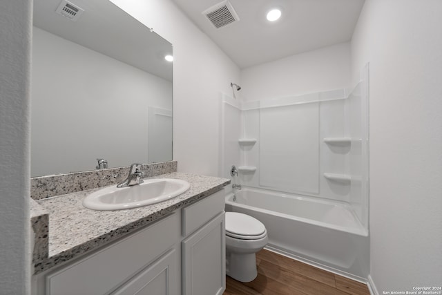 full bathroom with washtub / shower combination, vanity, hardwood / wood-style flooring, and toilet