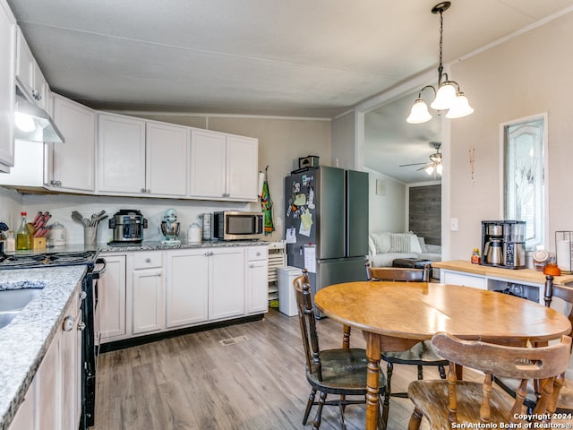 kitchen featuring light stone countertops, white cabinetry, appliances with stainless steel finishes, and vaulted ceiling