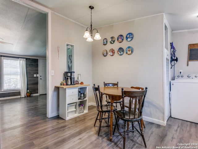 dining room with washer / clothes dryer, crown molding, wood-type flooring, and an inviting chandelier