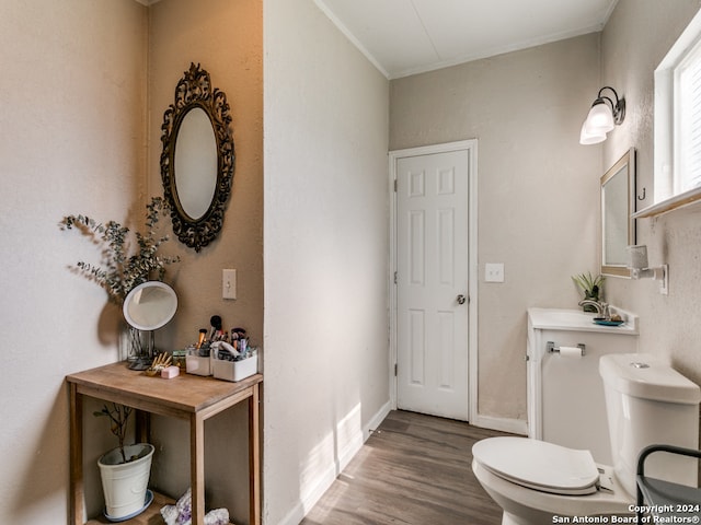 bathroom with hardwood / wood-style flooring, toilet, and ornamental molding