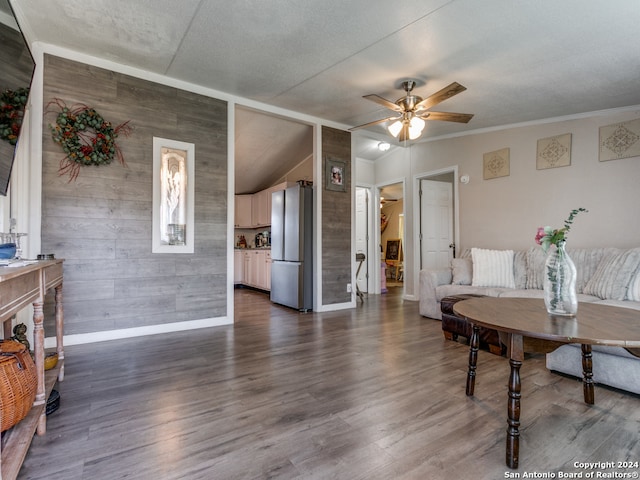 living room featuring ceiling fan, wood walls, dark wood-type flooring, and vaulted ceiling