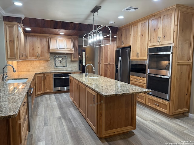 kitchen with visible vents, an island with sink, stainless steel appliances, pendant lighting, and a sink