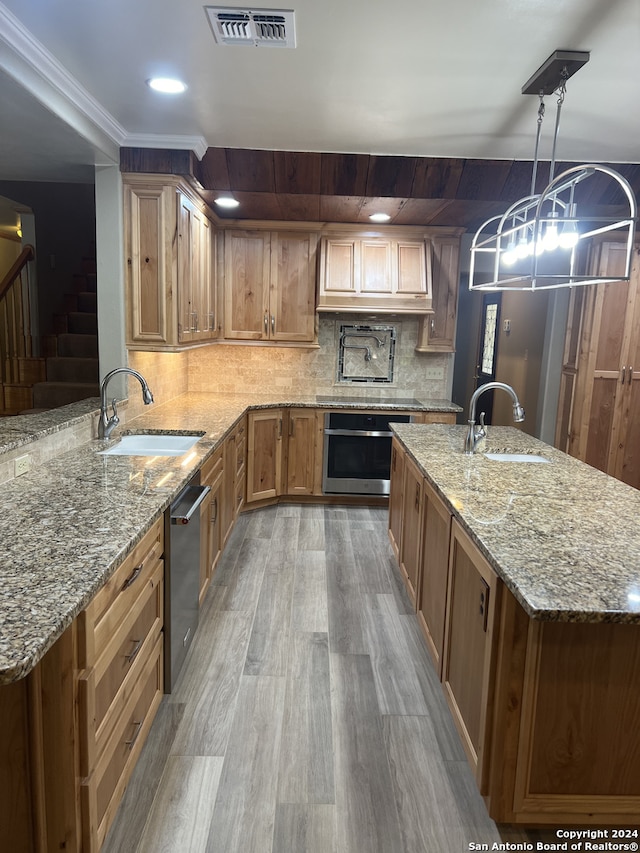 kitchen with light stone counters, visible vents, hanging light fixtures, appliances with stainless steel finishes, and a sink