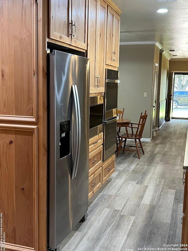 kitchen featuring baseboards, appliances with stainless steel finishes, light wood-style flooring, and ornamental molding