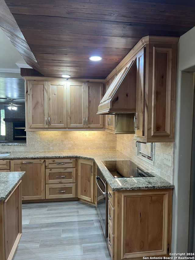 kitchen featuring custom exhaust hood, backsplash, wall oven, light stone countertops, and black electric cooktop