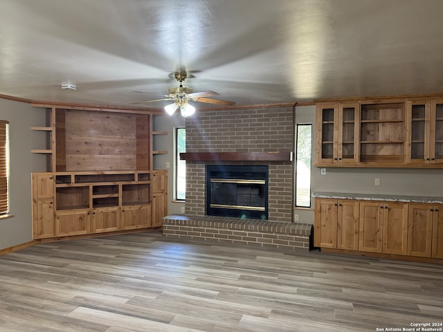 unfurnished living room featuring light wood-type flooring, ceiling fan, and a fireplace