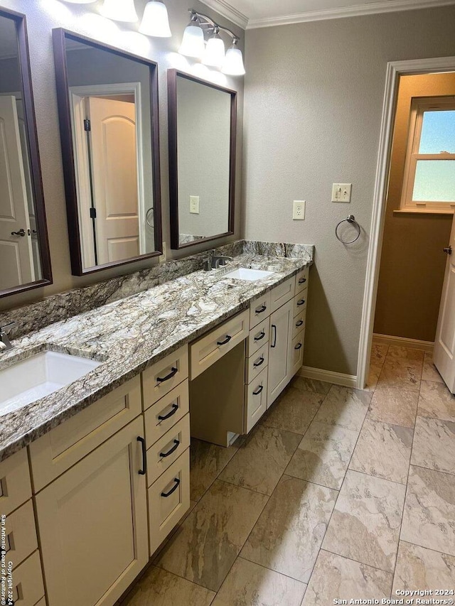 full bath featuring double vanity, ornamental molding, a sink, and baseboards