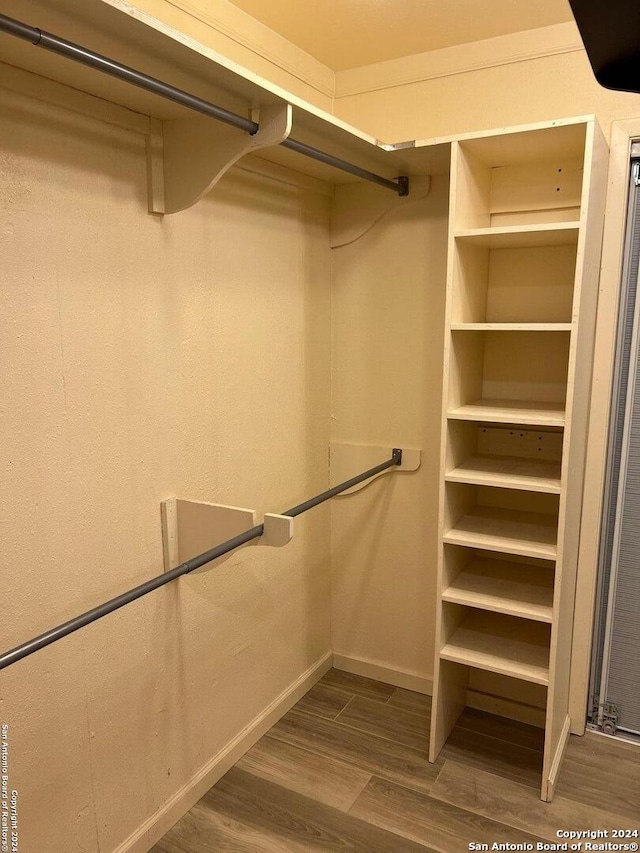 walk in closet with wood finished floors