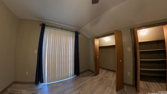 interior space featuring baseboards, ceiling fan, vaulted ceiling, light wood-type flooring, and a closet