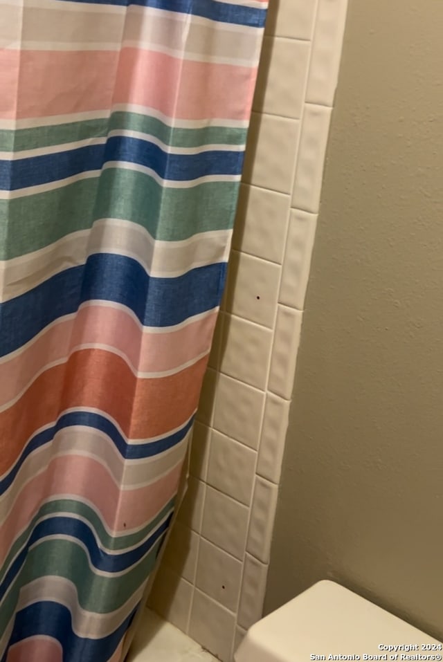 full bathroom featuring curtained shower and a textured wall