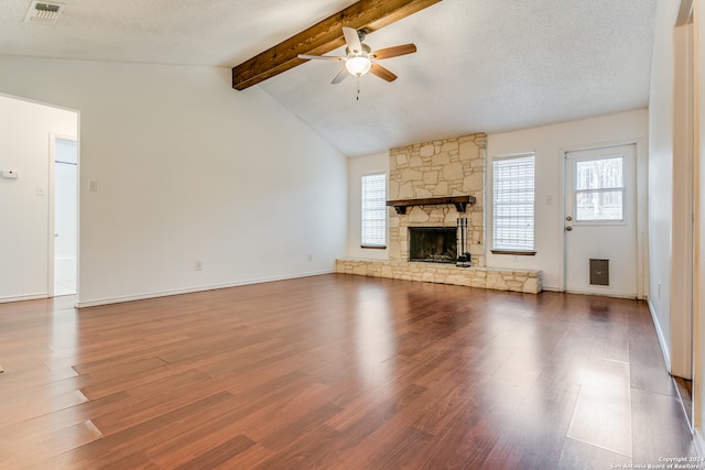 unfurnished living room featuring a textured ceiling, hardwood / wood-style flooring, and a stone fireplace