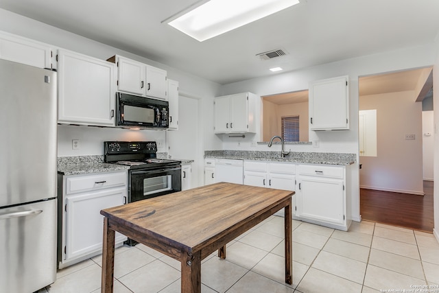 kitchen featuring light stone countertops, white cabinets, and black appliances