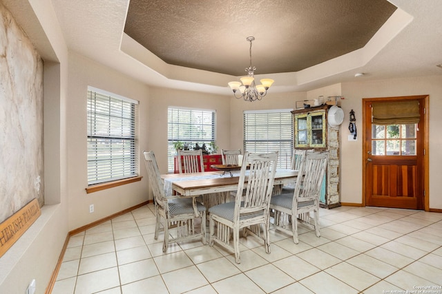 tiled dining area featuring a notable chandelier, a raised ceiling, and a textured ceiling