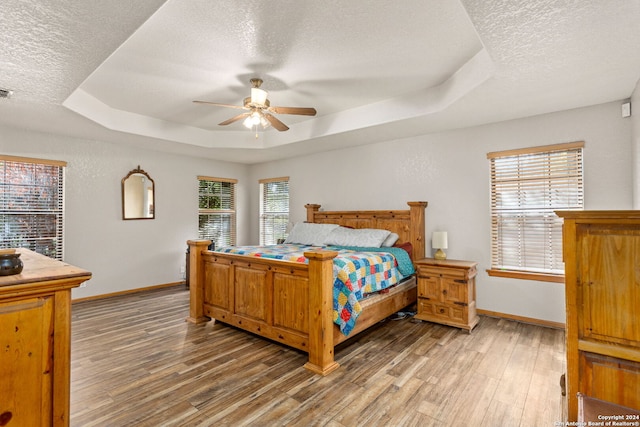 bedroom with hardwood / wood-style flooring, ceiling fan, a textured ceiling, and multiple windows