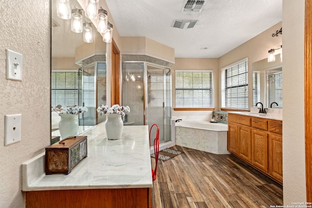 bathroom featuring wood-type flooring, vanity, a textured ceiling, and separate shower and tub