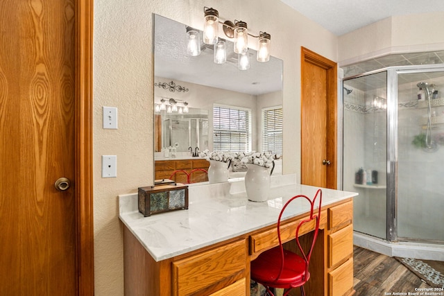 bathroom with a shower with door, vanity, a textured ceiling, and hardwood / wood-style flooring