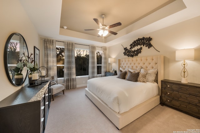 bedroom with a tray ceiling, ceiling fan, and light colored carpet