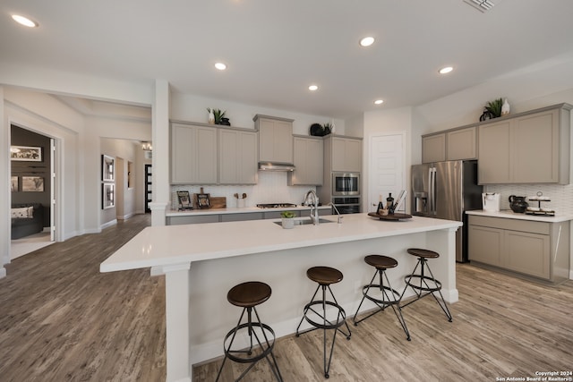 kitchen with a kitchen breakfast bar, a kitchen island with sink, sink, and stainless steel appliances