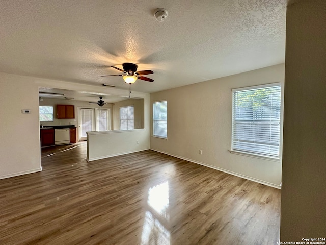 unfurnished living room featuring ceiling fan, dark wood-type flooring, and a textured ceiling