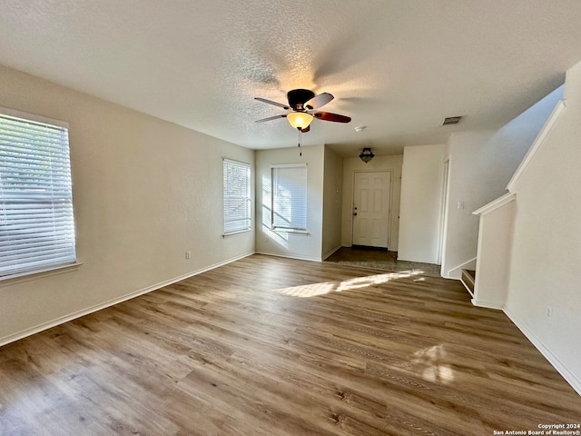 unfurnished living room with a wealth of natural light, ceiling fan, a textured ceiling, and hardwood / wood-style flooring