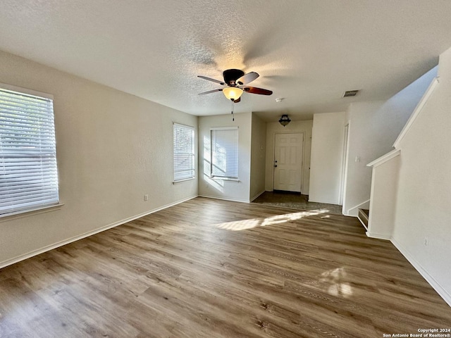 330 Agency Oaks, San Antonio, TX 78249 - unfurnished living room with healthy amount of natural light, a ceiling fan, wood finished floors, stairs, and a textured ceiling