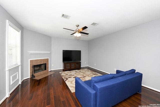 living room featuring a fireplace, ceiling fan, and dark wood-type flooring