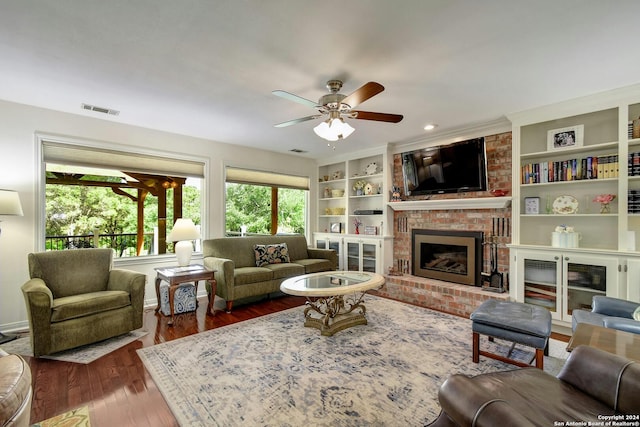 living room featuring a fireplace, built in shelves, dark hardwood / wood-style flooring, and ceiling fan